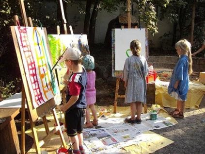 kleine Kinder malen an der Staffelei im Hof