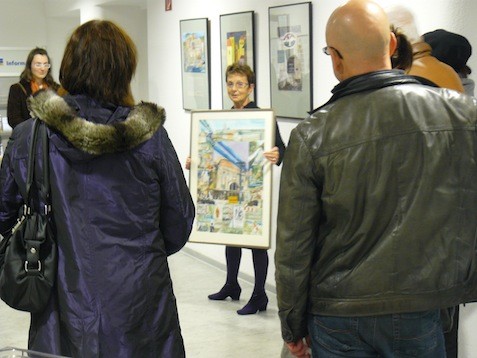 Frau erklärt den Besuchern einer Ausstellung ein Bild