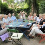 ältere Damen und Herren sitzen um ein Tisch herum im Hof des Haus Steinstrasse