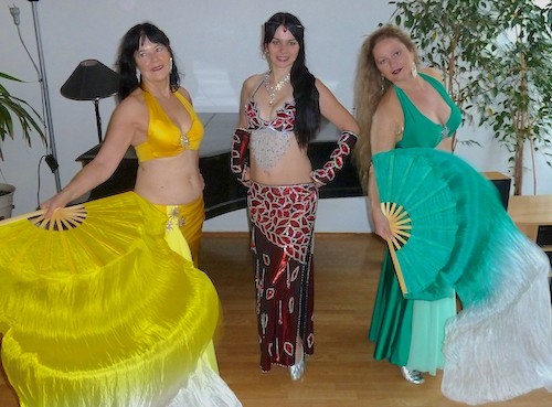 Drei Frauen tanzen mit bunten Kostümen