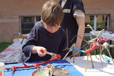 Junge gestaltet Objekt mit Ästen und Farbe