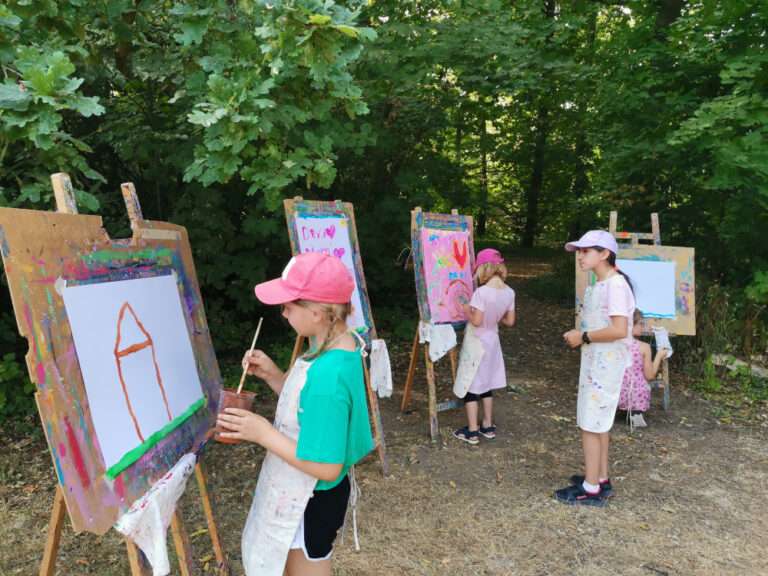 Kinder stehen an Staffelei und malen