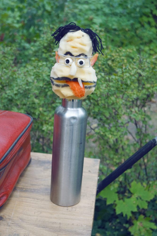 Auf einer Flasche steckt ein selbst gebauter Puppenkopf.