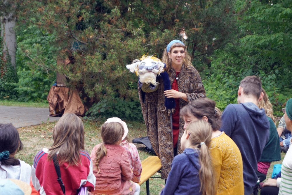 Eine Puppenspielerin, steht während der Aufführung im Publikum und bezieht Kinder mit in das Stück vom Glücksdrachen ein.