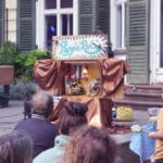 Mit dem Publikum sehen wir die witzig gestaltete Bühne von Pupp'n'Roll. 2 Puppen sitzen in einem Wohnzimmer und sehen sich ihre Lieblingsshow im Fernsehen an.