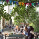 Im sonnigen Hof des Haus Steinstraße findet ein Fest statt, Personen unterhalten sich.