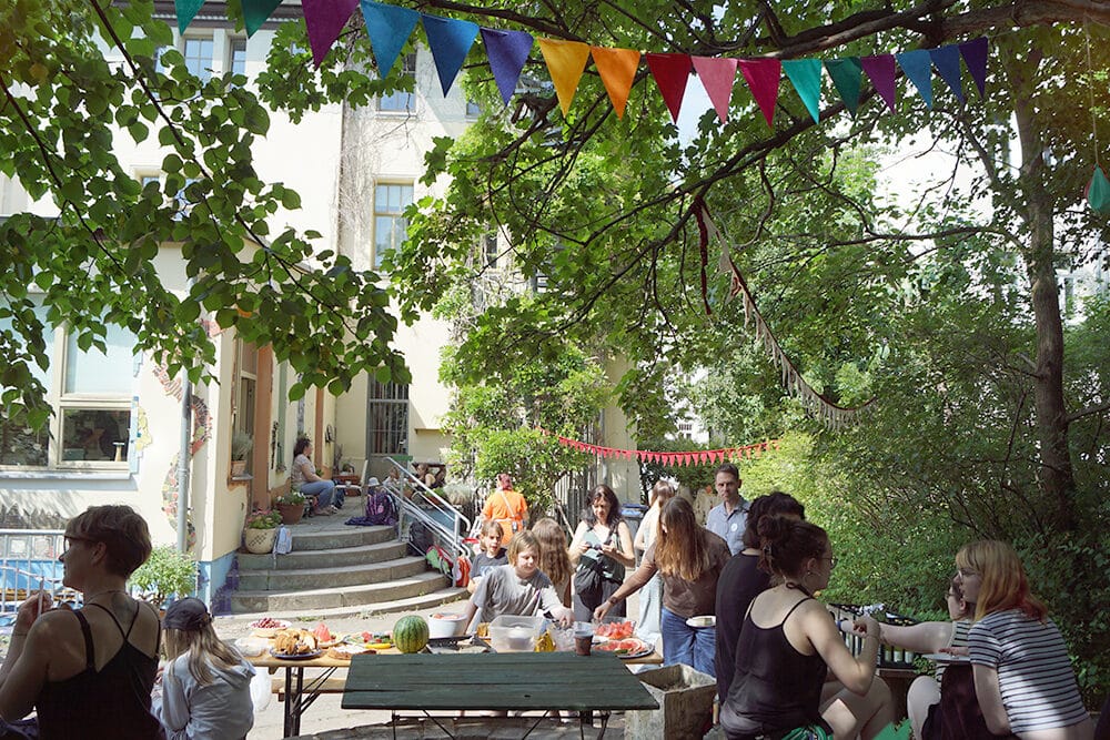 Im sonnigen Hof des Haus Steinstraße findet ein Fest statt, Personen unterhalten sich.