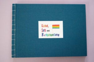 Dunkelblaues Buchcover mit weißer Bindung, das den Buchtitel und eine Regenbogenflagge zeigt