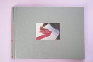 Graues Buchvover mit roter Bindung und einem Foto auf dem eine Hand, die malt und der Buchtitel zu sehen ist